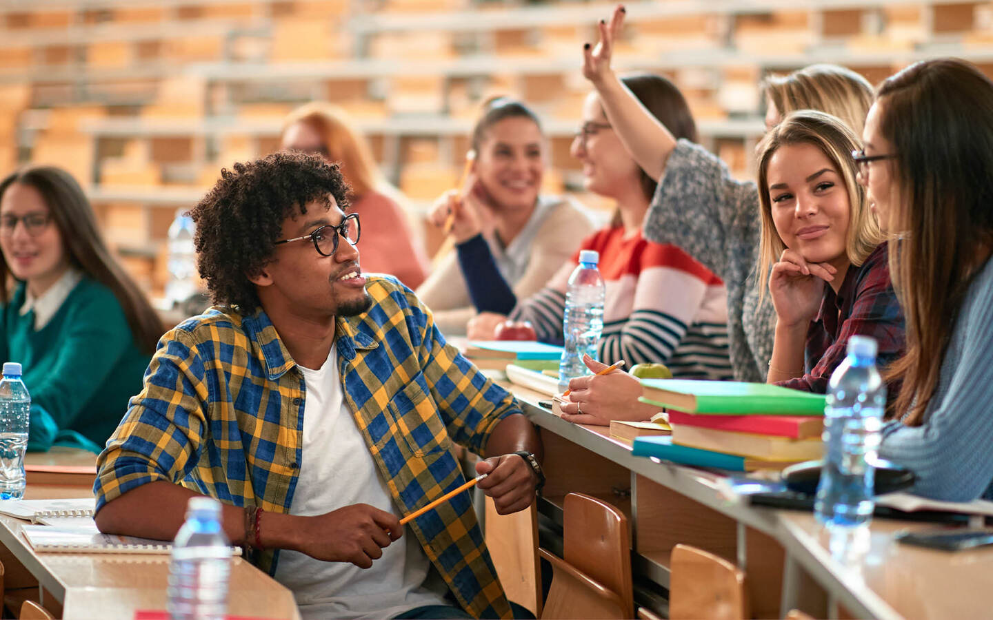 Étudiants souriants échangeant en amphithéâtre pendant un cours
