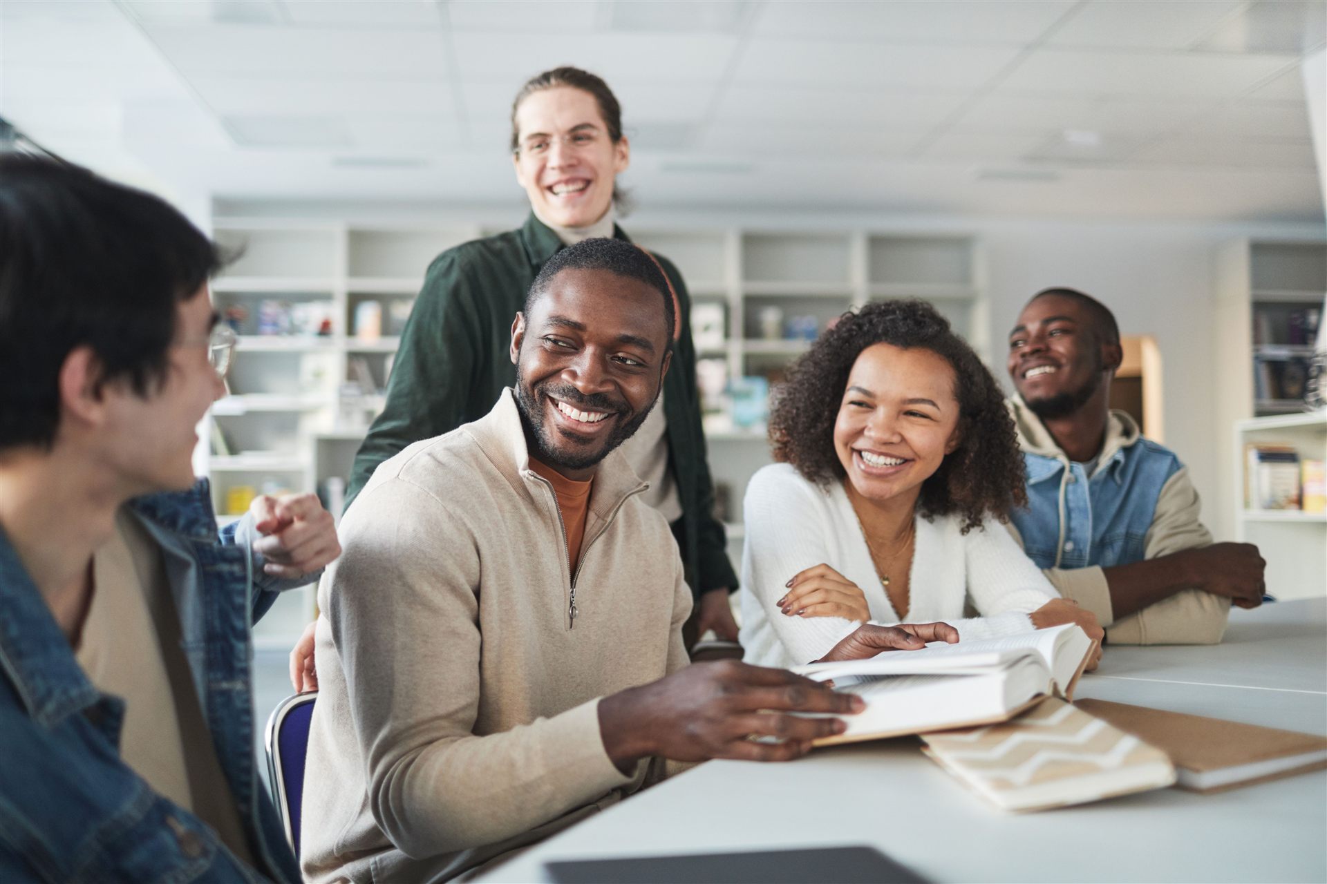 Groupe d'étudiants souriants échangeant autour d'une table à la bibliothèque