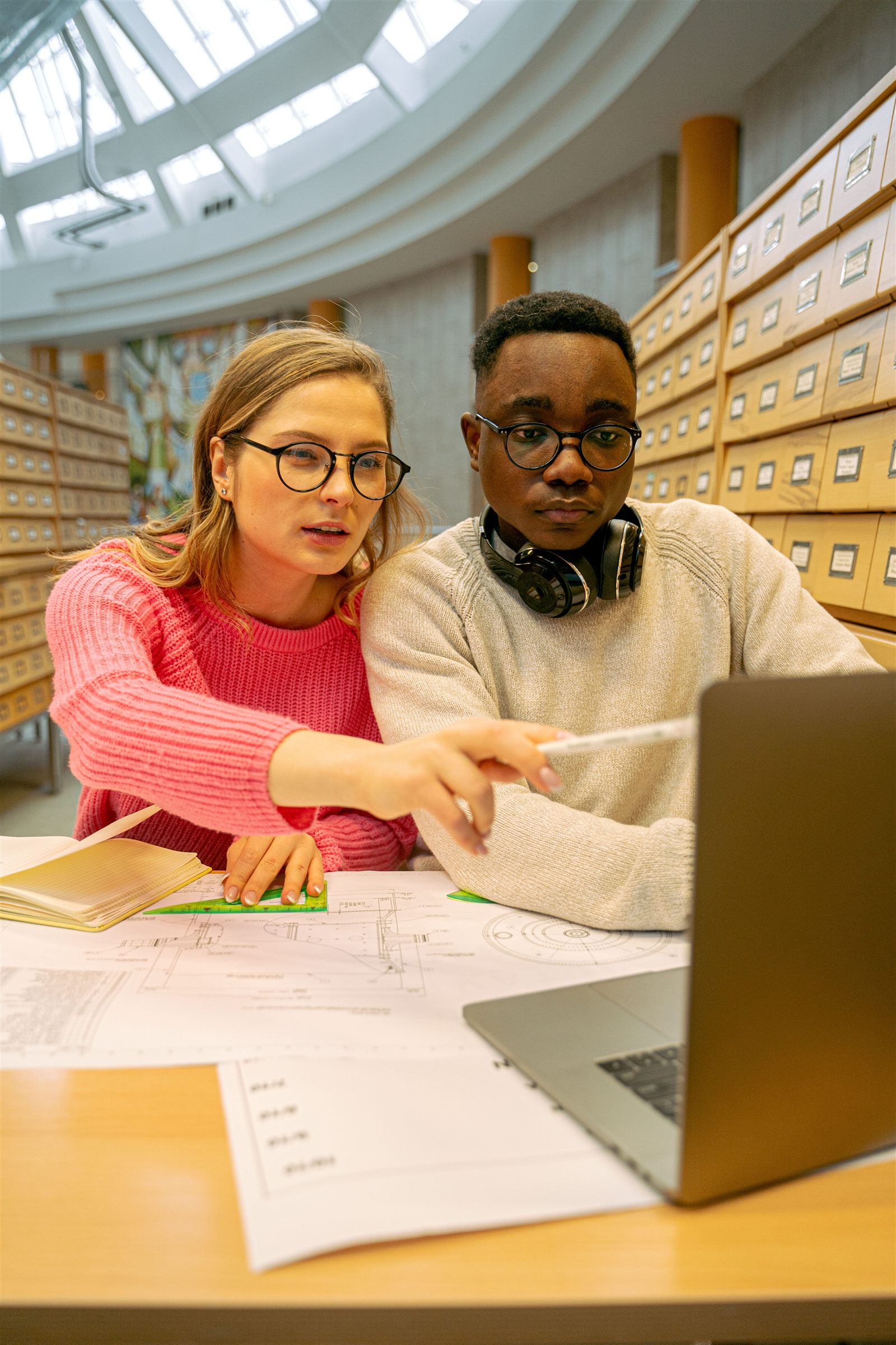 Deux étudiants consultant des plans et un ordinateur portable