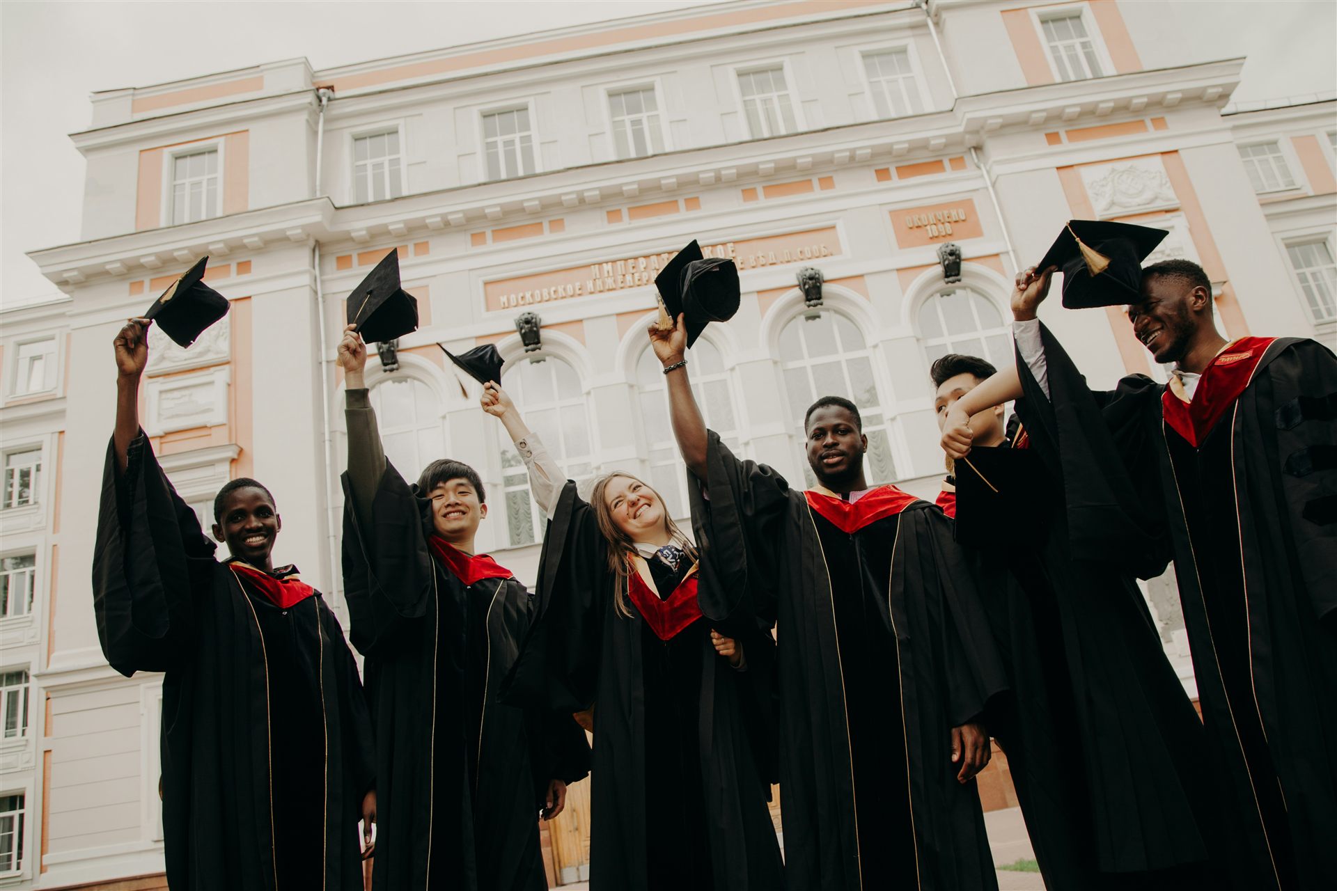 Groupe de jeunes diplômés levant leur toque en signe de réussite